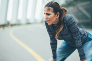 Exhausted sportswoman taking breath after workout