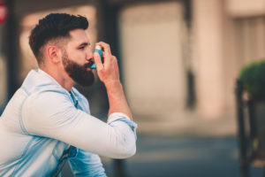 Men using asthma inhaler outdoor