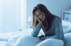 woman awake in the night she is touching her forehead and suffering from insomnia