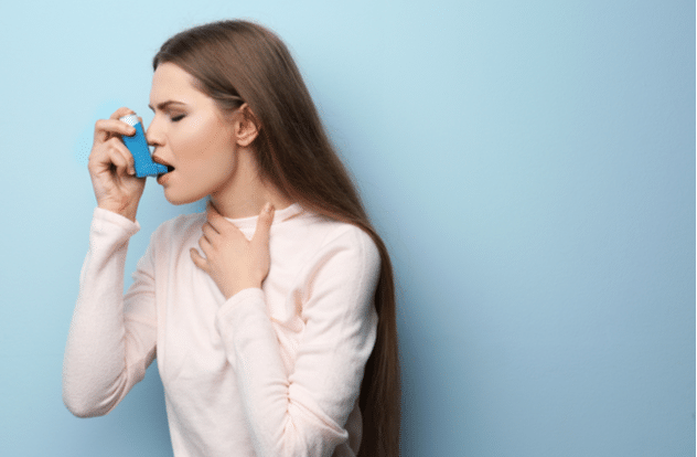 Young woman using asthma inhaler