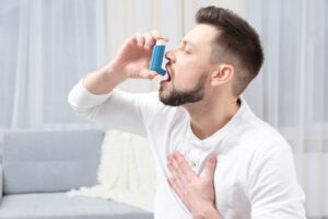 Young man using asthma inhaler at home